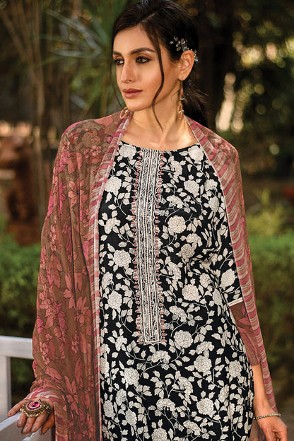 A woman wearing a black and white floral printed kurta with a pink sheer printed dupatta, standing outdoors against a blurred green background. | Wholesale Embroidered 3 Piece Kurta set | Sri Fashion
