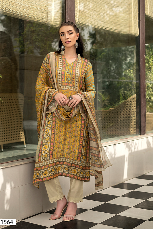 A woman models a traditional South Asian suit set. The outfit features a mustard yellow and orange printed suit with intricate geometric and floral patterns, paired with beige trousers and a matching dupatta. | Wholesale Mustard Yellow Muslin Suit Set | Sri Fashion
