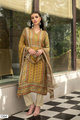 A woman models a traditional South Asian suit set. The outfit features a mustard yellow and orange printed suit with intricate geometric and floral patterns, paired with beige trousers and a matching dupatta. | Wholesale Mustard Yellow Muslin Suit Set | Sri Fashion
