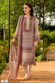 A woman modeling a traditional three-piece suit set in an outdoor garden setting. The suit features a beige suit with intricate multicolor geometric patterns, matching patterned trousers, and a coordinating dupatta with a red border. | Wholesale Beige Ethnic Muslin Suit Set | Sri Fashion
